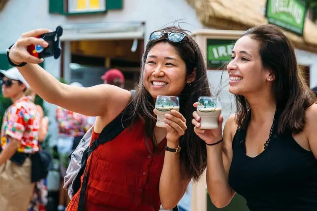 Photo of 2 women outside the Ireland food kiosk at Epcot taking a selfie with a drink.
