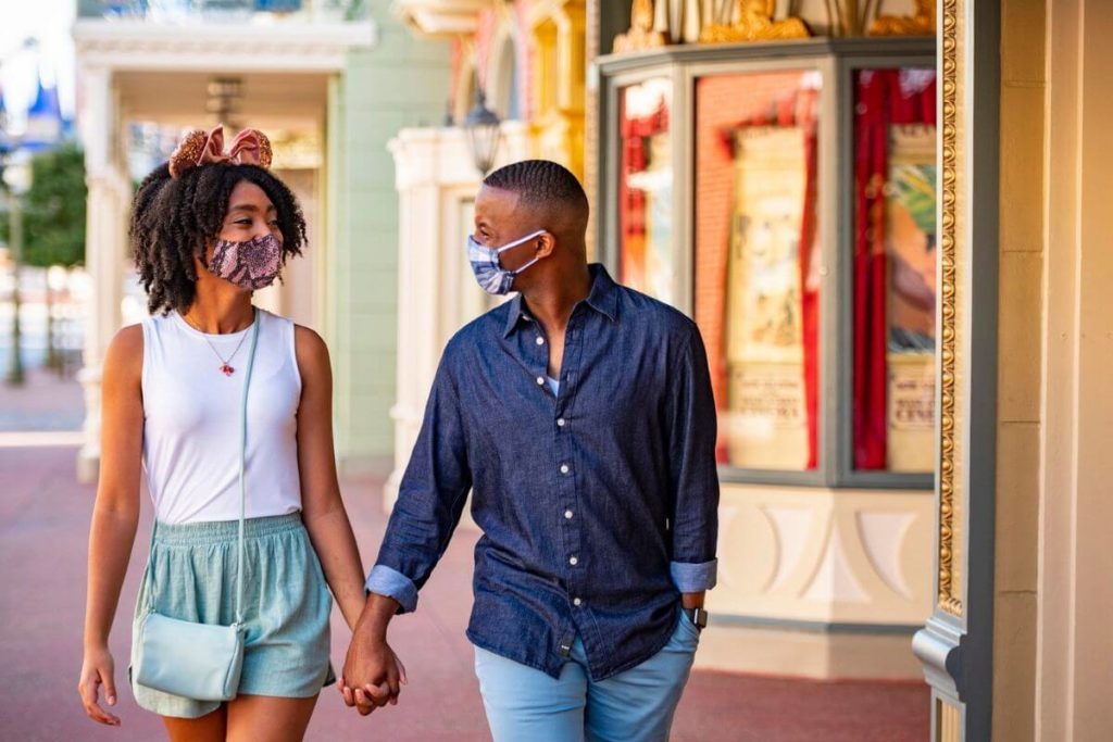 Close up of a couple a Disney World, holding hands while looking at each other adoringly.