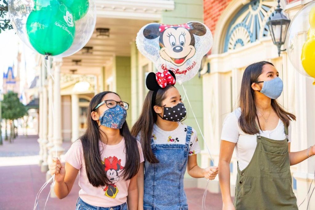 ディズニー-ワールドにいる間に保護マスクを着用した女性と2人の子供の写真。