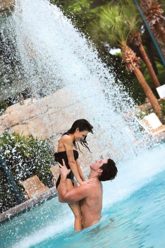 Close up of a couple a Disney World, holding hands while looking at each other adoringly.