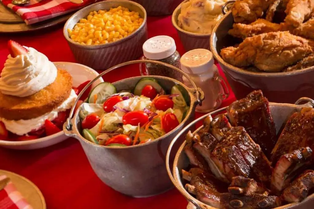 Closeup photo of a table with buckets and bowls full of barbecue foods.