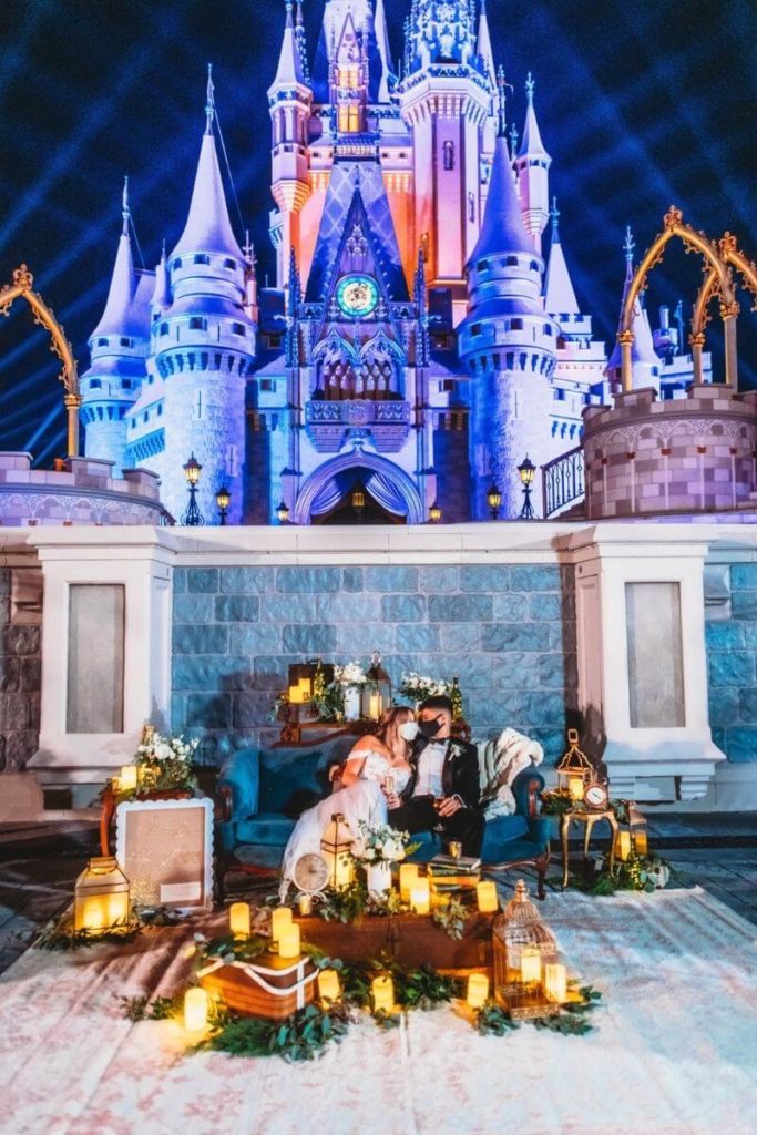 A couple poses in an elaborate settee at the foot of Cinderella's castle at Disney World's Magic Kingdom.