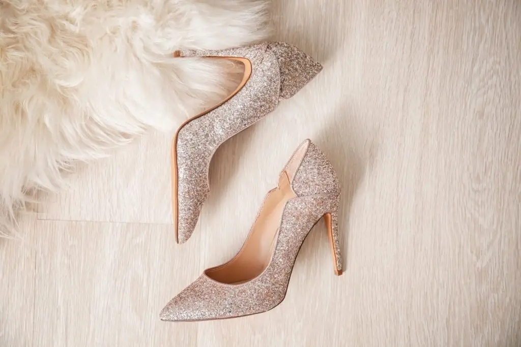 Photo of silver glittery high heels laying on a faux fur rug and wooden floor.