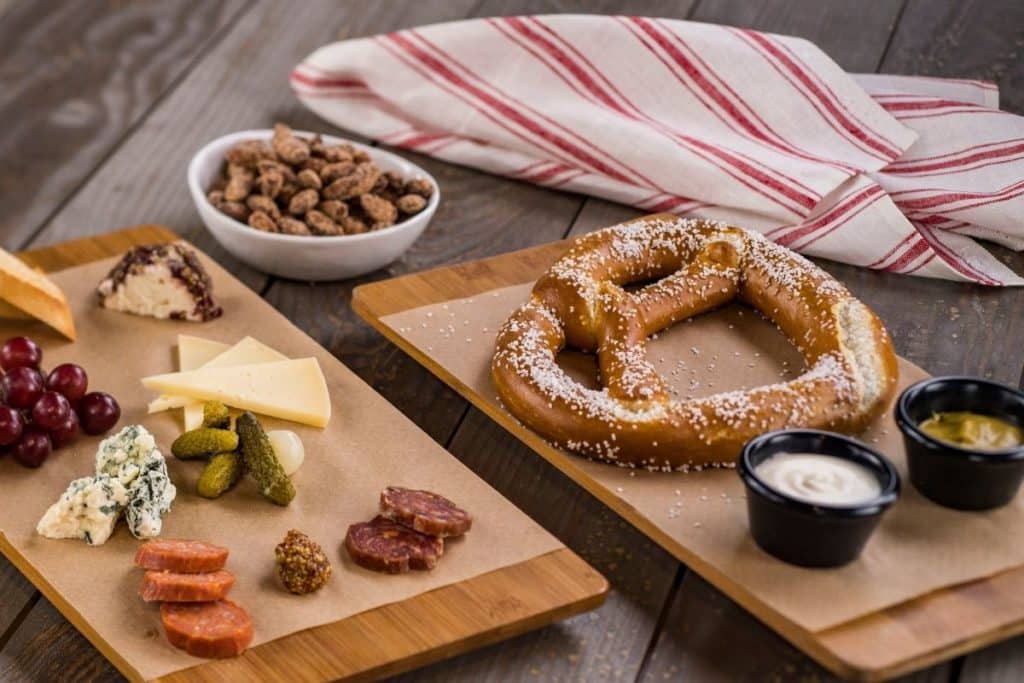 Photo of a charcuterie board and a giant pretzel, both arranged neatly on wooden cutting boards.