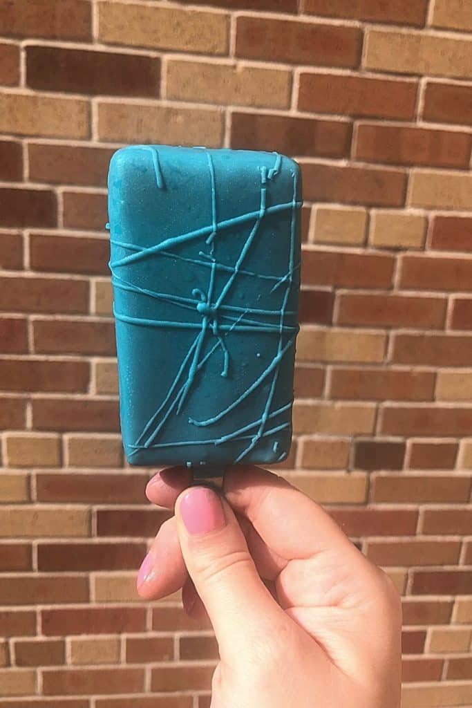 Closeup of a blue candy coated treat on a stick.