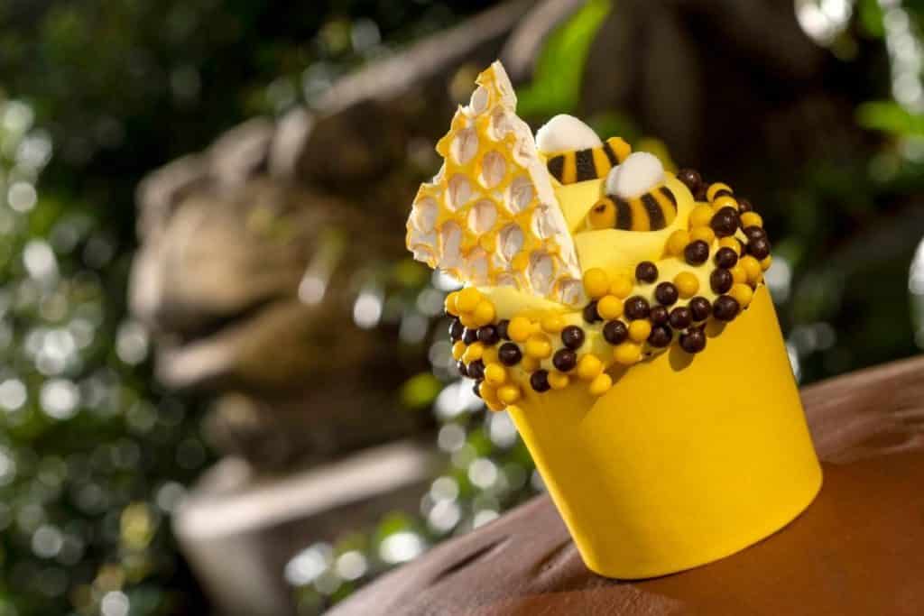 Closeup of a cupcake with yellow frosting, a candy honeycomb, candy bumblebees, and yellow and black candy pearls on top from Disney World's Animal Kingdom.