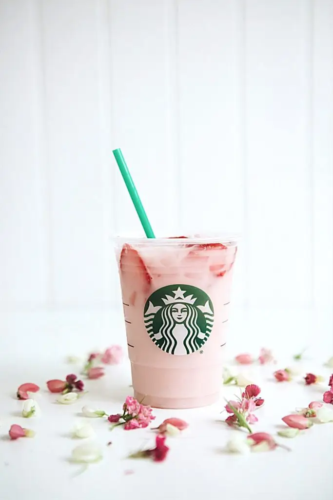 Photo of the pink drink with strawberries from Starbucks with pink and white flower buds artfully arranged around it.
