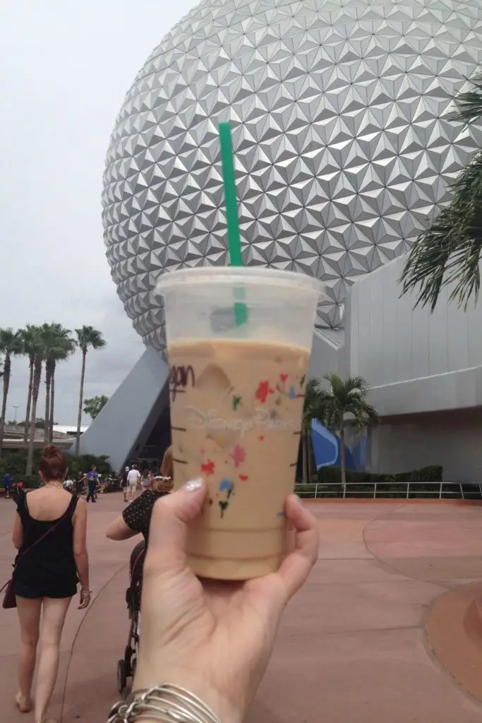 Closeup of a venti iced coffee from Starbucks at Epcot with the Epcot ball in the background