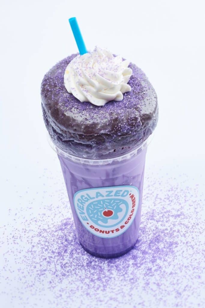 Closeup of the Purple Reign combo (iced chai with ube coconut milk and a purple ube glazed donut) from Everglazed Donuts & Cold Brew in Disney Springs.