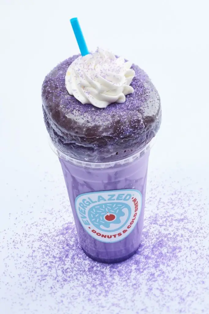 Closeup of the Purple Reign combo (iced chai with ube coconut milk and a purple ube glazed donut) from Everglazed Donuts & Cold Brew in Disney Springs.