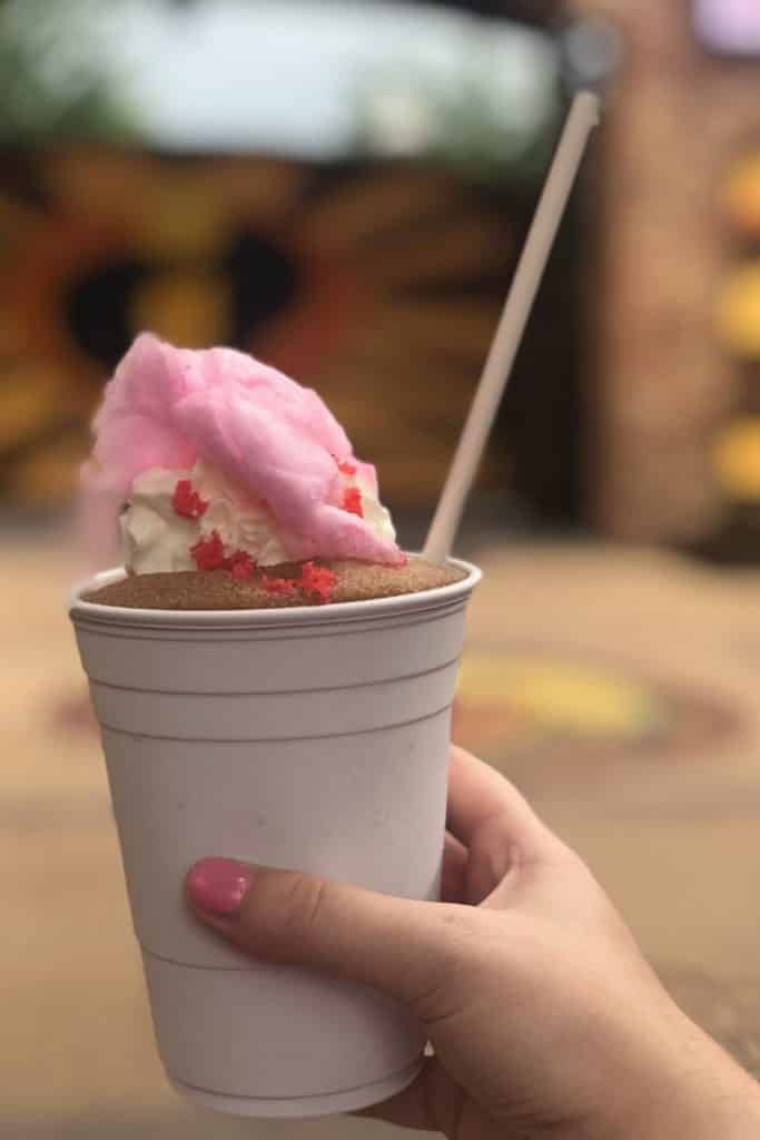 Closeup of a frozen coke slushy with pink cotton candy, whipped cream, and red popping candy.