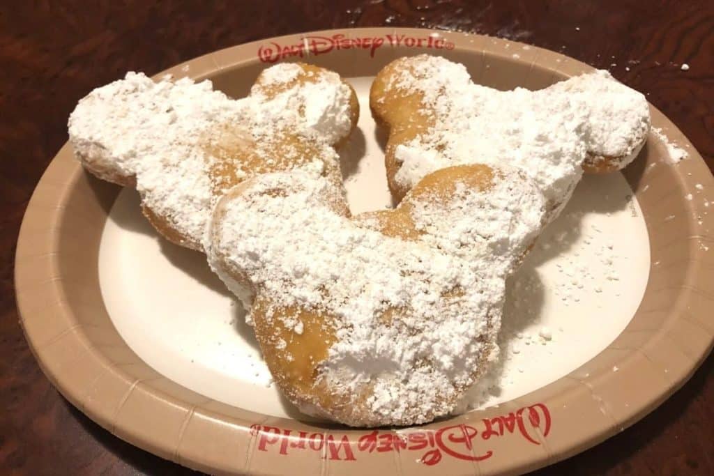 Closeup of 3 Mickey beignets covered in powdered sugar.
