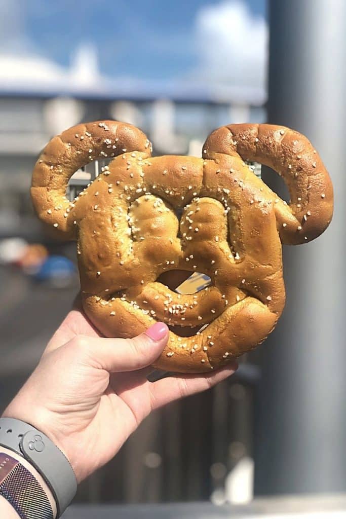 Closeup of a woman holding a large Mickey Mouse pretzel, one of the most popular snacks at Disney World.