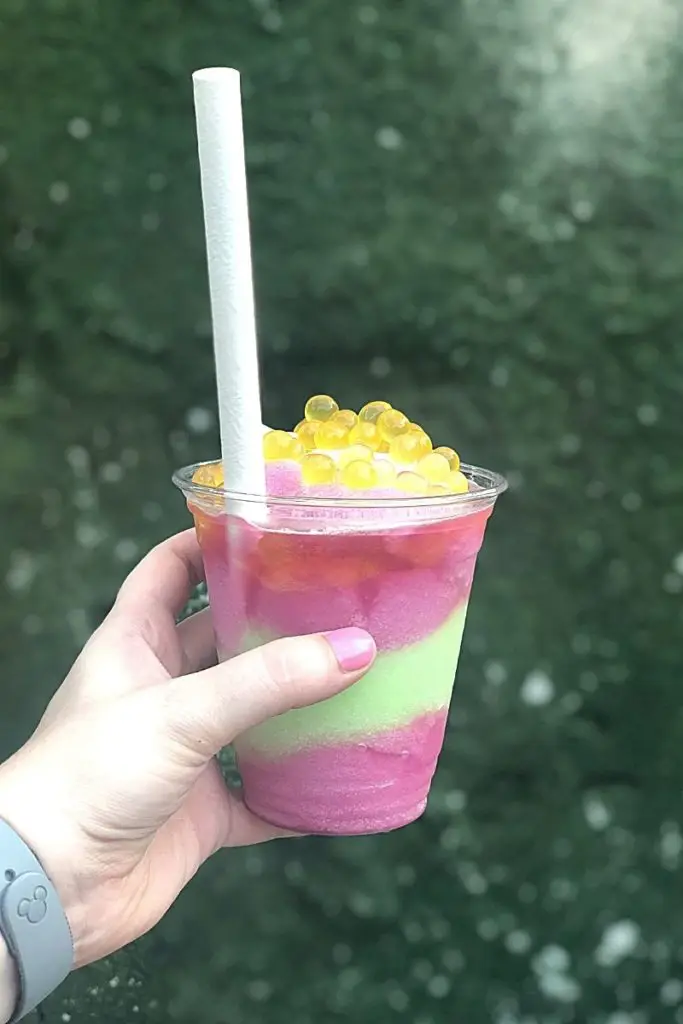 Closeup of a pink and green Night Blossom slushy with yellow boba on top.