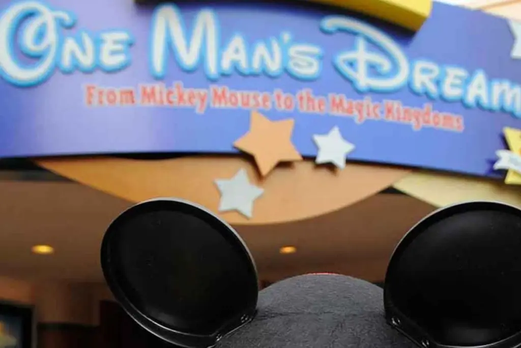 Closeup of a person wearing a Mickey Mouse ear hat in front of the entrance to One Man's Dream at Disney World's Hollywood Studios.