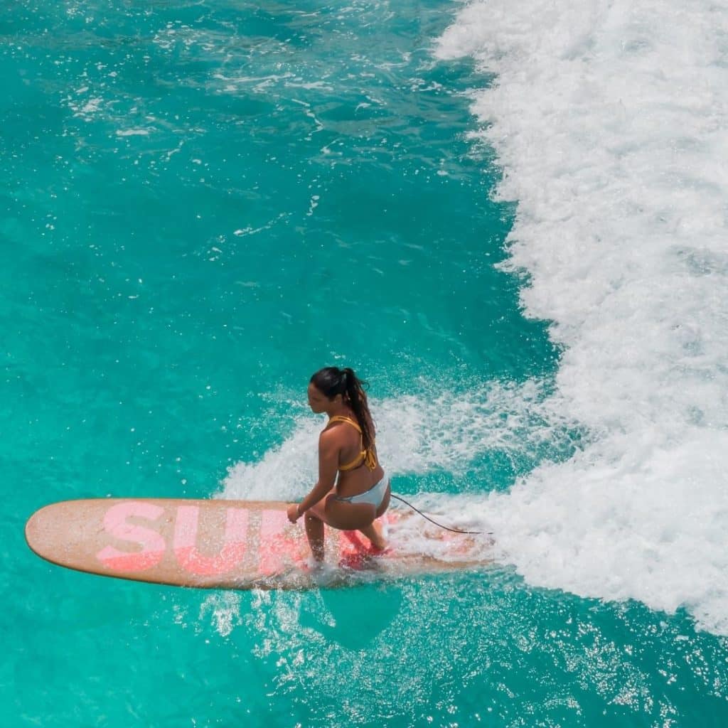 Aerial photo of a woman surfing in turquoise waters.