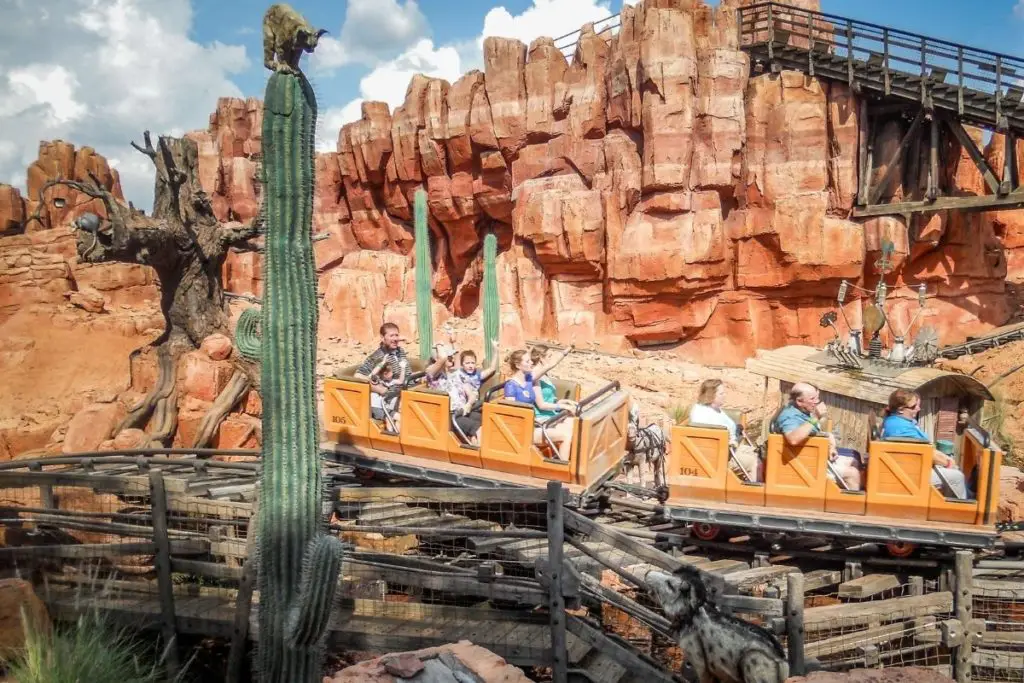 Photo of people riding the Big Thunder Mountain Railroad roller coaster at Magic Kingdom.