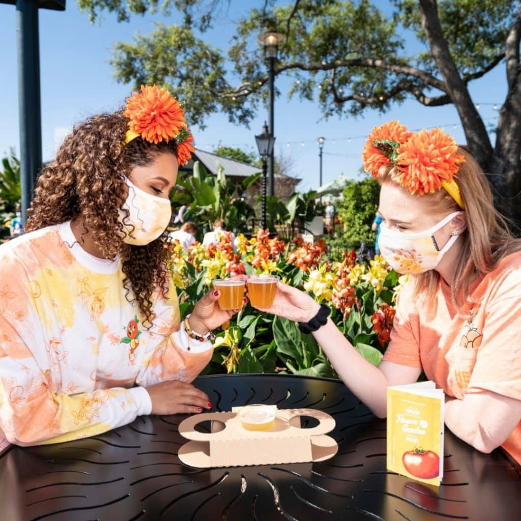 Photo of 2 women at the Epcot Flower & Garden Festival clinking beer samples.