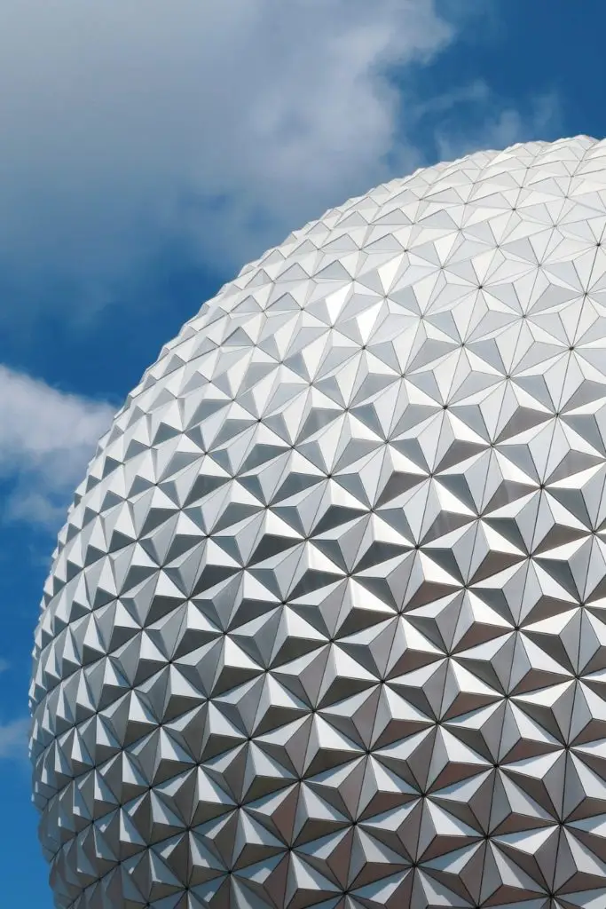 Closeup of the Epcot ball during the day set amidst cloudy skies.