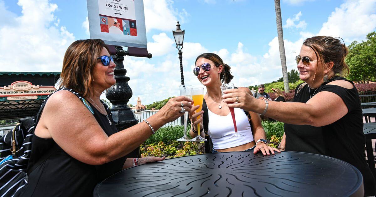 Photo of 3 women wearing tank tops while enjoying a cool beverage at Disney World's Epcot theme park.