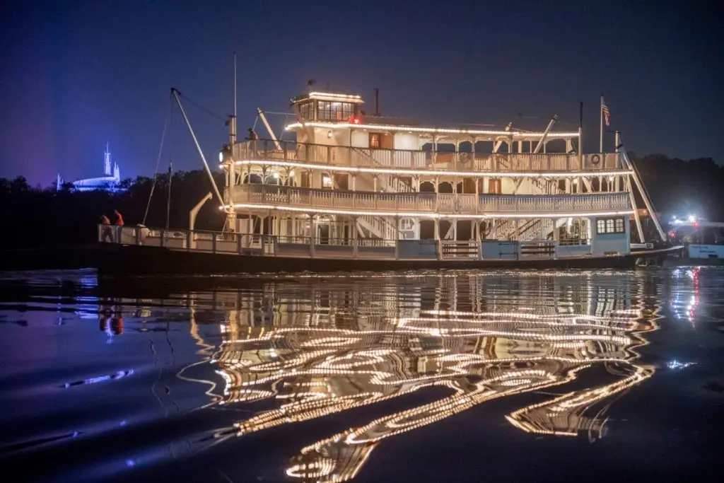 Photo of the Liberty Belle paddleboat ride all lit up at night, reflecting in the lake.