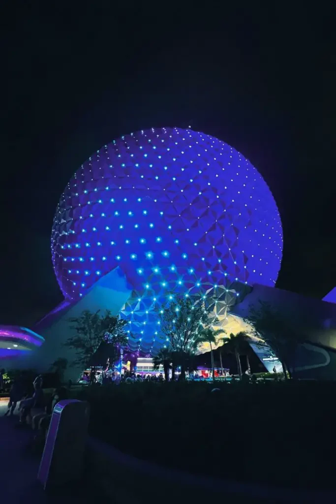 Closeup of the Spaceship Earth Epcot ball at night, light up with blue and turquoise lights.
