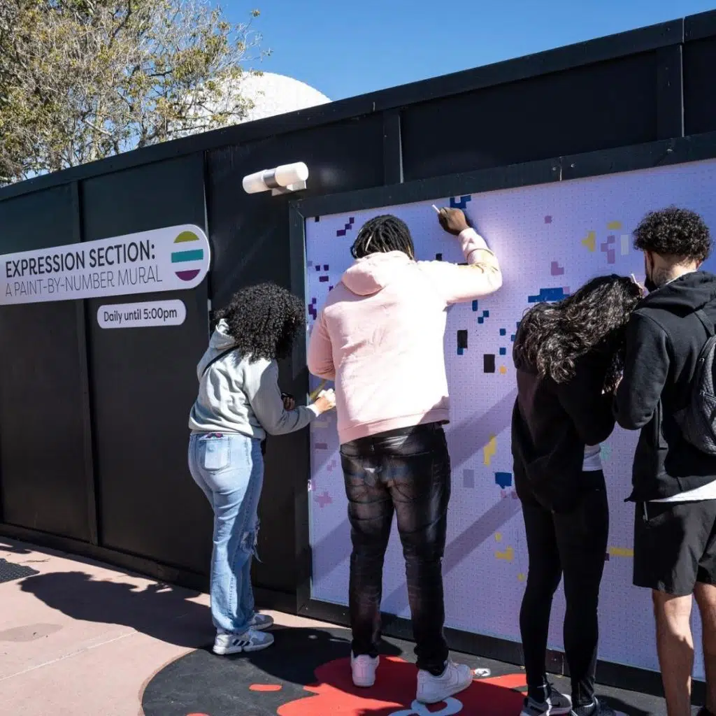 Photo of people painting in squares of a mural at Epcot theme park.