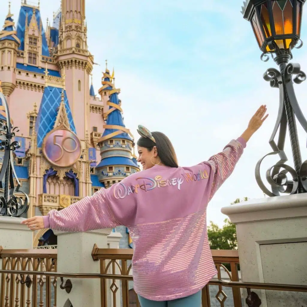 Photo from behind a woman posing in front of Cinderella's Castle at Disney World's Magic Kingdom.