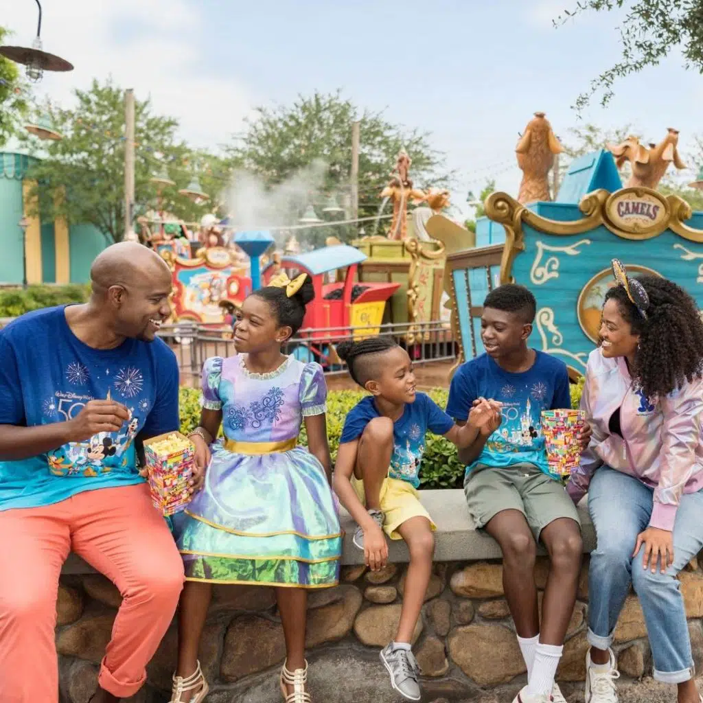 Photo of a mom and dad with 3 kids, enjoying popcorn at Magic Kingdom.