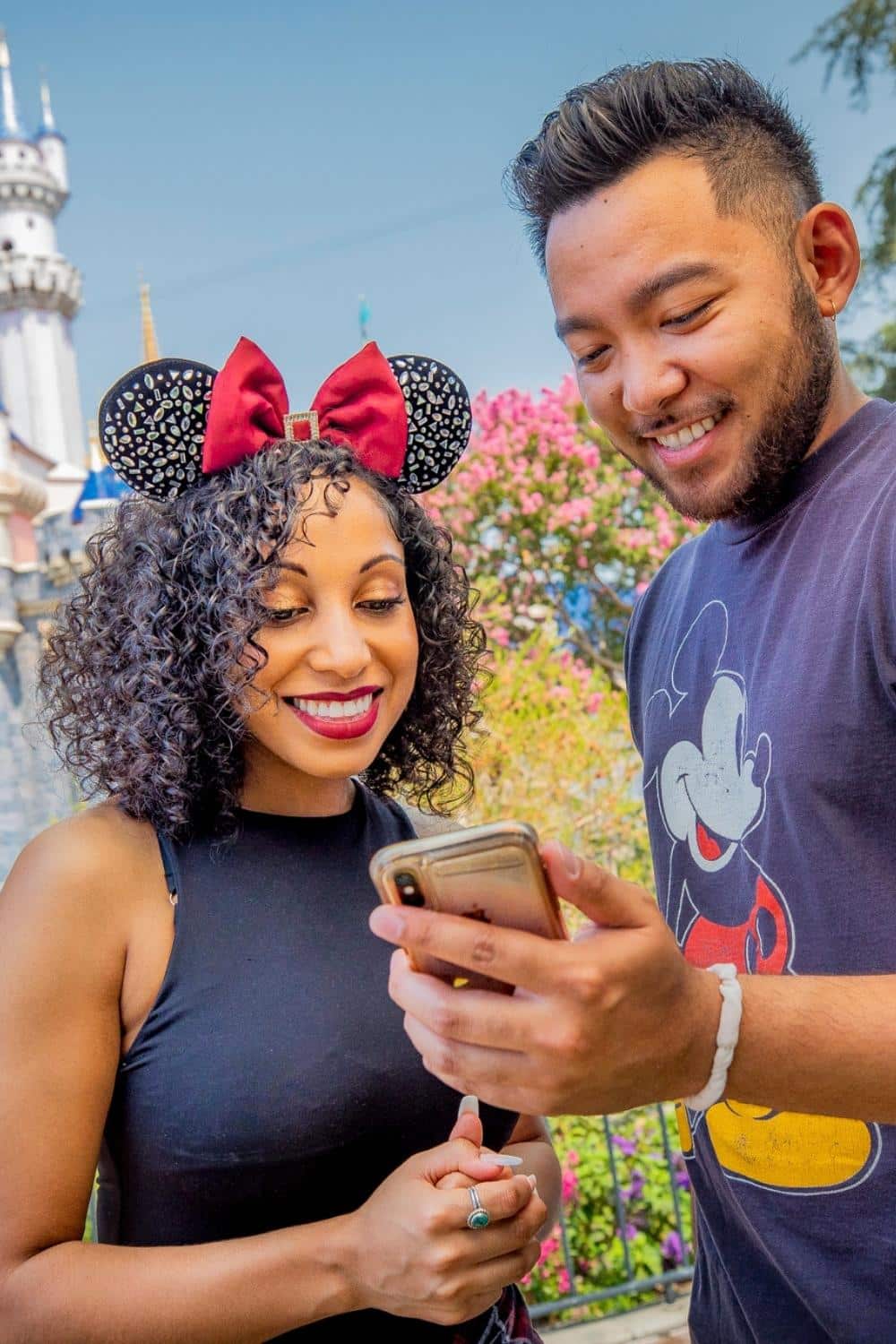Photo of a man and woman looking at a mobile phone while at Disneyland.