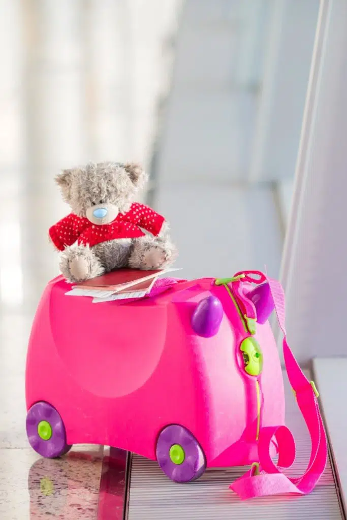 Photo of a trunki luggage for kids with a teddy bear sitting on top.