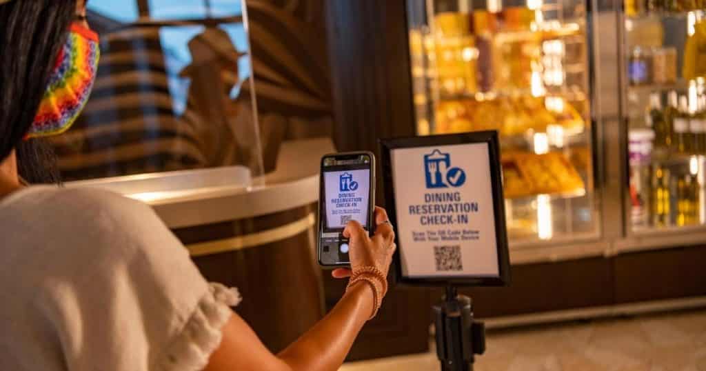 Photo of a woman checking into her dining reservation via mobile phone.