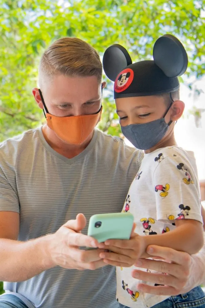 Photo of a dad and his son at Disneyland, looking at the Disney World app.
