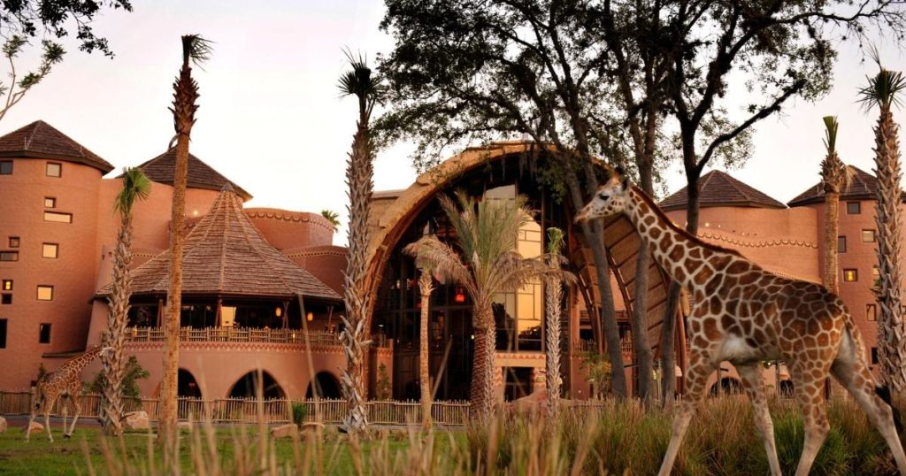 Photo of Animal Kingdom Lodge in the background with giraffes roaming the savanna in the foreground.