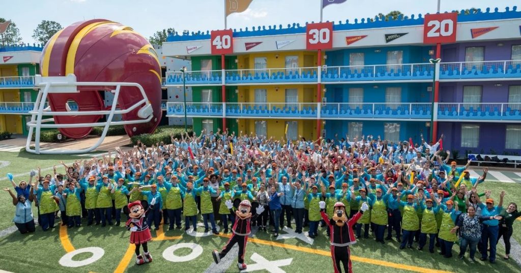 Photo of Disney cast members, Minnie Mouse, Mickey Mouse, and Goofy posing outside the All Star Sports Resort.