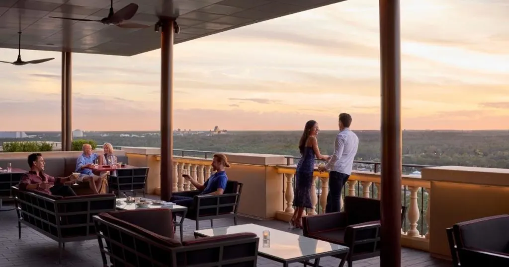 Photo of adults enjoying a cocktail on a balcony during sunset at the Four Seasons Orlando.