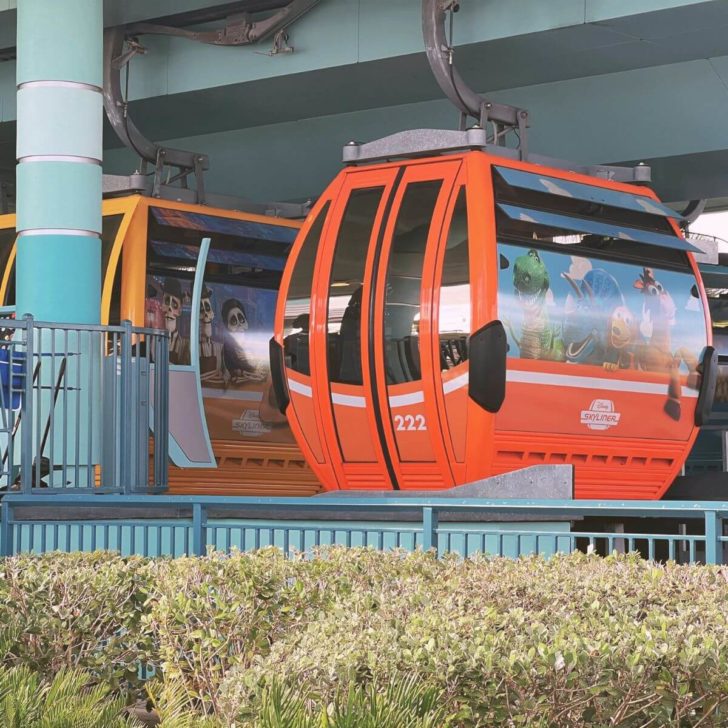 Closeup of Disney Skyliner cabins, one adorned with Toy Story characters and another with Coco characters.