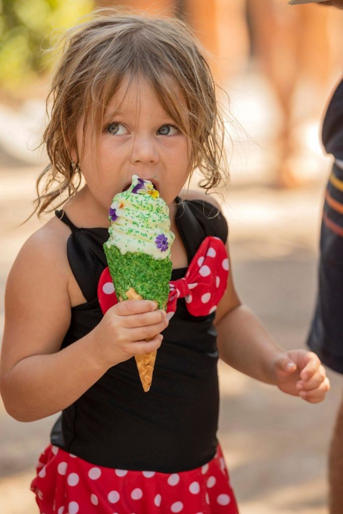 Photo of a young girl eating a soft serve ice cream cone.