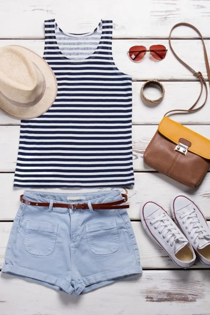 Flat lay photo of a Summer outfit: tank top, short, hat, sunglasses, and Converse sneakers.