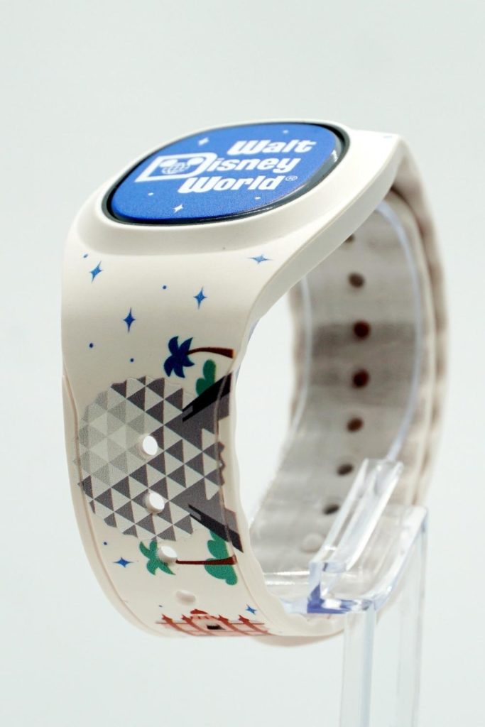Closeup of a white MagicBand Plus for Disney World with graphics from the theme parks on it.
