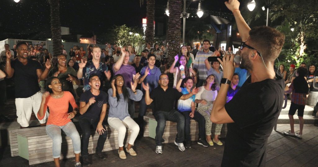 Photo of a man singing to an audience at Disney Springs.
