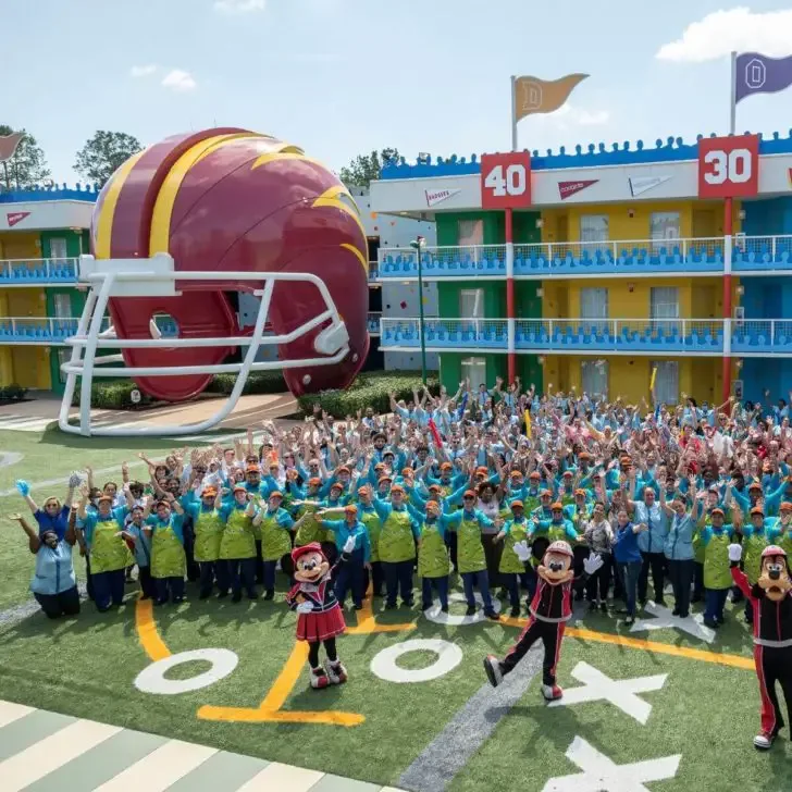 Photo of the All-Star Sports Resort with the entire cast posing outside with Minnie, Mickey, and Goofy.
