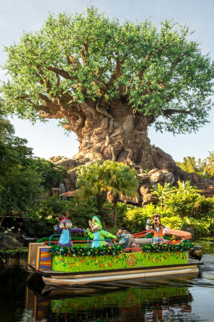 Photo of Chip, Dale, and Goofy on a flotilla cruising the Discovery River at Disney World's Animal Kingdom with the tree of life in the background.