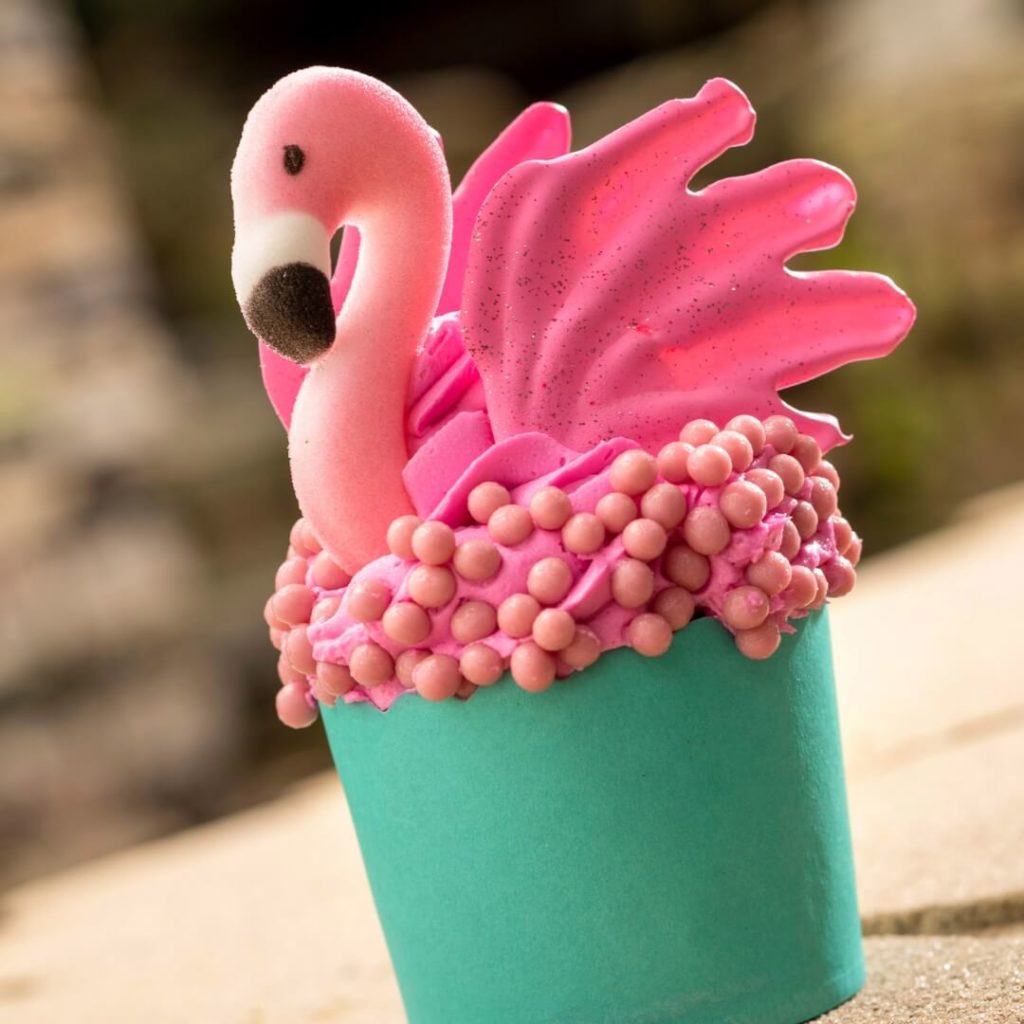 Closeup of a cupcake adorned by a bright pink flamingo.