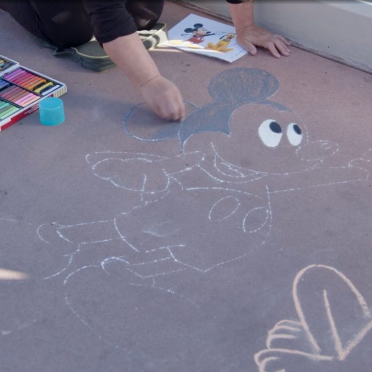Photo of a person drawing Disney chalk art at the Epcot Festival of the Arts.