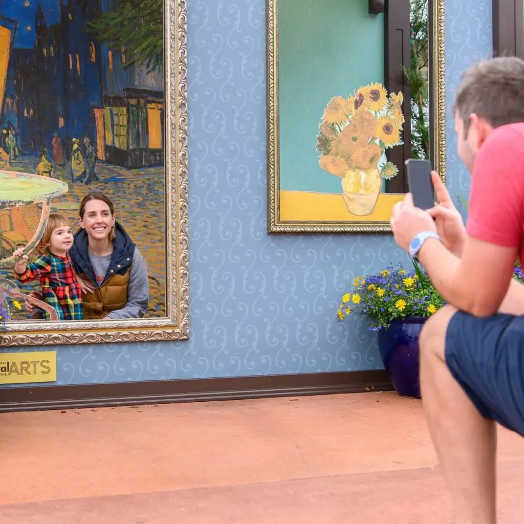 Photo of a man taking a photo of a woman and child at an art-themed photo op.