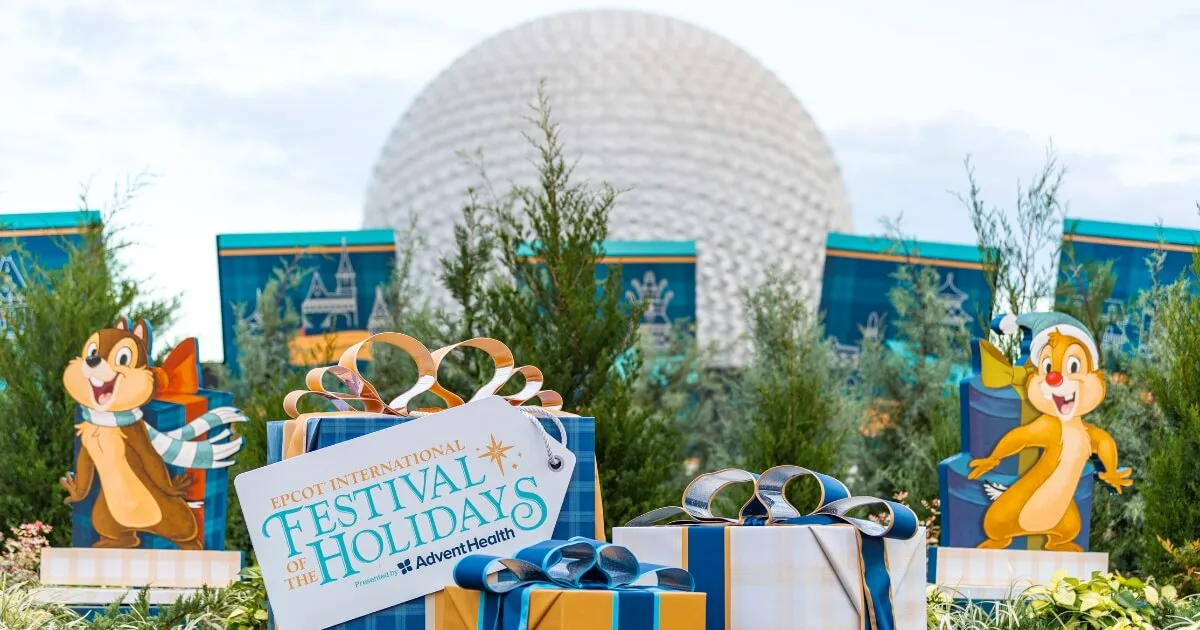 Photo of the signage for the Epcot Festival of the Holidays with gift packages and Chip and Dale with Spaceship Earth in the background.