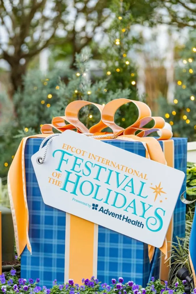 Closeup of a gift package with a sign that says "Epcot International Festival of the Holidays Presented by AdventHealth."
