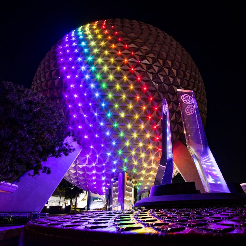 Photo of Spaceship Earth at Epcot at night with a rainbow projected onto it.