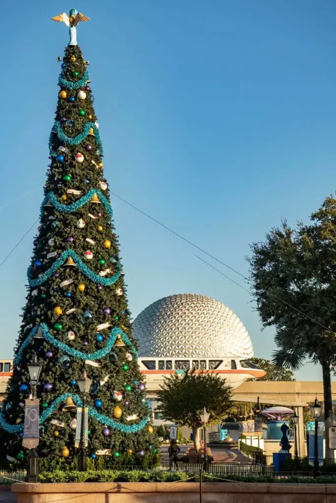 Photo of a Christmas tree with the monorail and Epcot's Spaceship Earth in the background.
